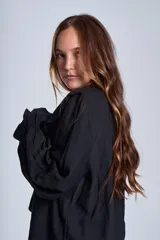 Blusa de color marrón con escote en V, mangas largas abullonadas con puños elásticos y detalles de volados en los hombros y el frente.