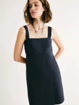 Vestido corto de corte recto con escote cuadrado, tirantes anchos y bolsillos laterales. Diseño minimalista con costura horizontal bajo el busto.