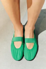 Zapato tipo bailarina de estilo deportivo color verde, con tira ancha elástica y detalle de fruncidos en el empeine. Cuenta con talonera en contraste de materiales, suela plana engomada y acabado en punta redonda.