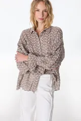 Camisa celeste a rayas verticales blancas, con cuello clásico, cierre frontal con botones y mangas largas abullonadas con puños elásticos.