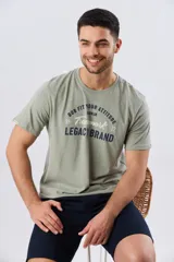Remera verde pistacho de manga corta y cuello redondo, con diseño gráfico estampado en el frente con inscripciones y tipografías en tonos oscuros y blancos.
