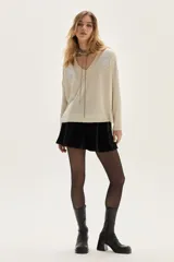 Sweater de tejido de punto con acabado brillante de lurex, escote en V y mangas largas. Presenta detalles de bordados florales en los hombros y un diseño con tajos laterales en el ruedo.