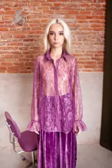 Camisa de encaje azul con cuello camisero, botones transparentes y mangas largas con volados en los puños.