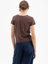 Remera de algodón pima orgánico color marrón, con cuello redondo y bordes de mangas en color rosa. Presenta un estampado frontal de cerezas con llamas.