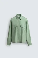 Camisa de corte relajado confeccionada en tejido fluido con mezcla de lyocell. Presenta diseño de rayas verticales, cuello solapa, manga larga con puños abotonados, bolsillos de plastrón con solapa en el pecho y cierre frontal con botones a presión.
