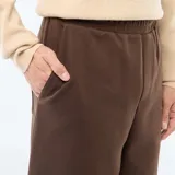 Pantalón de corte ancho y estilo relajado, confeccionado en tejido de color marrón, con cintura elástica y diseño minimalista.
