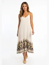 Vestido largo vaporoso de ramio, color blanco, con tirantes finos, silueta fluida y diseño bordado en el bajo.
