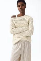 Pantalón amplio de punto, tiro alto, con cintura elástica y cordón ajustable. Presenta un diseño de rayas verticales en tonos beige y marrón claro.