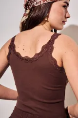Musculosa off white de algodón peinado elastizado, con calce al cuerpo, escote redondo y detalles de encaje en el escote y los tirantes.