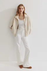 Campera oversized de sherpa suave color beige, con cuello elevado, cierre frontal y bolsillos discretos en las costuras laterales. Presenta hombros caídos y mangas largas amplias.