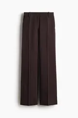 Pantalón sastrero de tiro alto y piernas rectas, color marrón, con pliegues frontales, trabillas para cinto y bolsillos.