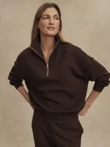 Buzo de tejido DoubleSoft® color café oscuro, con corte oversize, cuello alto con media cremallera dorada y puños amplios.