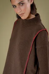 Buzo de lana color beige con cuello redondo y mangas largas. Presenta detalles de costuras decorativas bordadas en color naranja a lo largo de los laterales y en los puños.