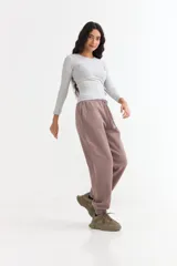 Pantalón jogger de felpa color marrón, con cintura elástica ajustable mediante cordón, bolsillos laterales y puños elásticos en los tobillos.