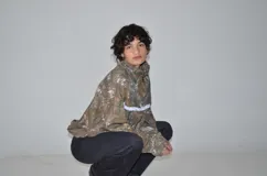 Campera de jogging con estampado de camuflaje tipo Real Tree, corte oversize y cierre frontal. Presenta un detalle de puntilla blanca en la parte superior delantera y un bordado a tono en el pecho.