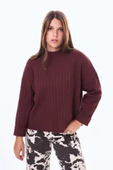 Buzo tejido de punto acanalado en color bordó, con cuello alto y mangas largas anchas con puños ajustados.