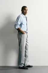 Pantalón denim de corte recto desde la cadera hasta el tobillo, de tiro medio y color celeste claro con efecto lavado. Cuenta con diseño clásico de cinco bolsillos y cierre frontal con cremallera y botón metálico.