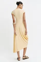 Vestido largo color amarillo pastel, confeccionado con mezcla de viscosa, con cuello redondo, manga corta y bajo asimétrico fruncido con volumen.