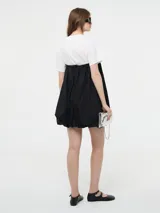 Vestido corto negro, estilo globo o balloon, con escote corazón pronunciado. Se lleva sobre una remera blanca de manga corta.