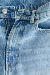 Jean tobillero barrel de tiro alto, confeccionado en denim de algodón rígido color celeste con efecto deslavado. Presenta diseño curvo en las piernas con volumen y tiras finas para atar en los bajos.