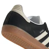 Championes Adidas modelo Samba OG, con diseño clásico de perfil bajo. Presentan una base de gamuza negra con las icónicas tres tiras laterales y puntera en tono crema, finalizando con una suela de goma color caramelo.