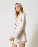 Blazer cruzado de lana color crudo, con solapas, cierre con botones a tono, manga larga con aberturas y bolsillos con solapa.