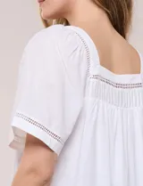 Blusa de corte holgado color marfil, confeccionada en mezcla de modal y algodón, con escote cuadrado y mangas cortas adornadas con detalles de puntilla calada.