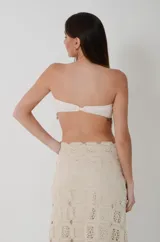Conjunto de bikini color marfil de crepé elastizado, compuesto por un corpiño strapless con detalle frontal de encaje crochet y cierre con broche en la espalda, y una bombacha de calce clásico con tiras laterales.