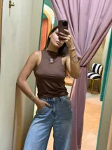 Musculosa tipo top halter de color marrón oscuro, ajustada al cuerpo, con cuello alto y logo bordado en el centro del pecho.