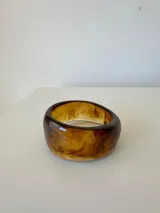 Pulsera rígida tipo brazalete de acrílico con efecto marmolado en tonos marrones y ámbar.