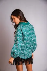 Camisa de manga larga con diseño abullonado, confeccionada en tela bordada con motivos florales. Presenta cierre frontal con botones y puños elásticos.