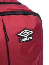 Mochila Umbro color bordó con base y detalles en negro. Presenta el logo de Umbro en blanco en el frente y un bolsillo lateral de malla.
