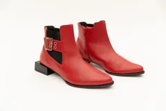 Botín de cuero negro con elásticos laterales, aplique metálico con ojales y cierre lateral con cremallera. Taco cuadrado desfasado de 3 cm.