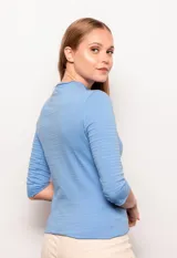 Polera manga 3/4 color lila, de corte ajustado y cuello alto con detalle de tela con textura a rayas horizontales.