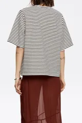 Camiseta de punto roma con rayas horizontales blancas y negras, corte recto y manga corta ancha. Presenta un escote redondo y un detalle de nervio vertical en el centro delantero.