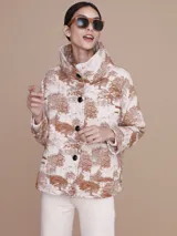 Saco acolchado con estampado toile de jouy en tonos beige y marrón, con cuello alto y cierre frontal con botones negros.