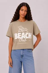 Remera de algodón de manga corta y cuello redondo, con diseño holgado y estampado frontal con la inscripción "Beach Club" y un gráfico de una reposera.