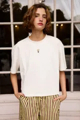 Remera de algodón color blanco, de corte holgado y manga corta, con un pequeño bordado de una flor en el centro del pecho.