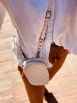 Bandolera pequeña color crudo con diseño acolchado en forma de rombos. Incluye correa larga regulable y tarjetero interno.