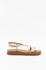 Sandalias planas color hueso con tiras cruzadas y hebilla ajustable. Suela de corcho.