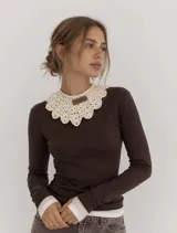 Cuello tejido a mano en lana merino, con diseño de encaje festoneado y etiqueta de cuero con marca grabada.