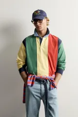 Polo de manga larga con diseño de rayas verticales anchas en colores amarillo, verde, rojo, azul marino y celeste. Cuenta con cuello camisero de denim y cierre frontal parcial con botones ocultos bajo solapa.