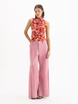 Top al cuerpo sin mangas con escote alto tipo polera y detalle de frunce en el centro delantero. Presenta un estampado full print de flores hibiscos en tonos rojos y naranjas sobre base celeste.