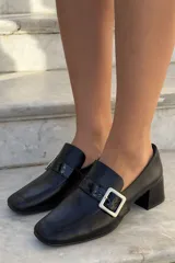 Mocasín de cuero vacuno color bordó con acabado charolado, punta cuadrada, taco bloque bajo y detalle de tira con hebilla metálica plateada en el empeine.