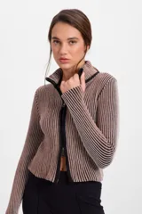 Campera corta de tejido de punto acanalado con diseño de rayas verticales en dos tonos. Presenta cuello alto y cierre frontal completo con borde en color negro.