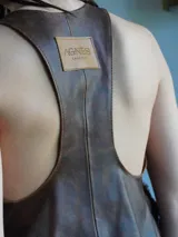 Chaleco marrón de cuero con bolsillos de corderito y lazos de ajuste frontales.