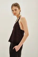 Top negro con escote en V y tirantes finos, ambos con detalles de encaje. Presenta un diseño de cadenas bordadas con cuentas en la parte frontal.