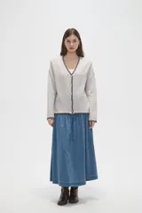 Cardigan de viscosa en color gris claro, con cuello en V, cierre frontal de botones y detalle de costuras en contraste color negro en los bordes.