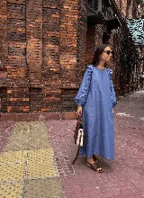 Vestido midi de corte holgado en color verde oliva, con mangas largas abullonadas que presentan detalles de volados en los hombros y puños elásticos.