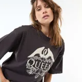 Camiseta de corte oversize color negro, con cuello redondo y mangas cortas. Presenta un estampado frontal en color crema con el logo de la banda Queen, rodeado de motivos florales y una corona.